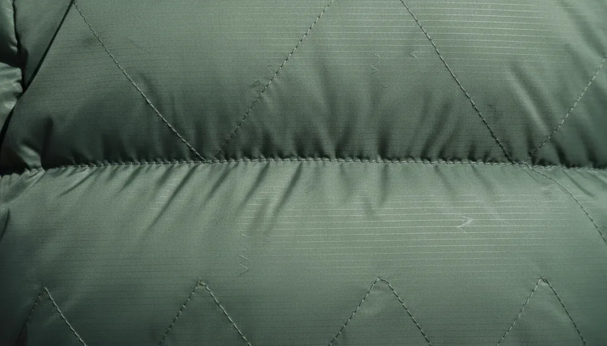 Close-up view of quilted puffer jacket stitching and weather-resistant fabric shell.