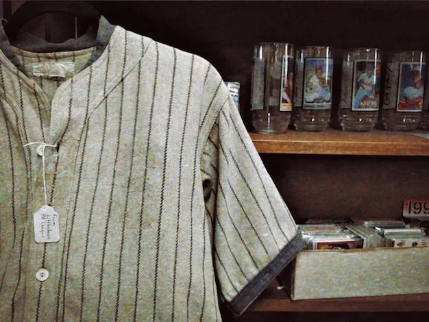 A close-up shot of a rack of vintage band t-shirts in a thrift store. The shirts feature various band logos and designs, with some showing signs of wear and tear. The lighting is warm and inviting, highlighting the unique character of each shirt.