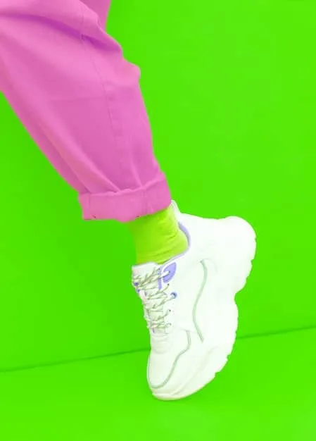 A split image featuring a pair of chunky sneakers with bold neon colors and oversized soles on one side, and minimalist white trainers with clean lines on the other, set against a gradient background.
