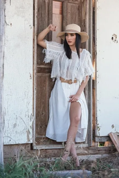 Shot of boho-chic outfit: white tee, maxi skirt, sandals, wide-brimmed hat.