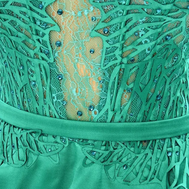 A close-up shot of a 3D printed dress highlighting the unique texture and material. The dress is made of a flexible, translucent material and features intricate geometric patterns. The lighting emphasizes the details and complexity of the design.