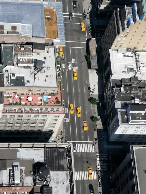 An aerial view of a bustling city street in a major US city (e.g., New York or Los Angeles), with pedestrians wearing a variety of luxury outerwear styles. This highlights the real-world application and visibility of these fashion trends.