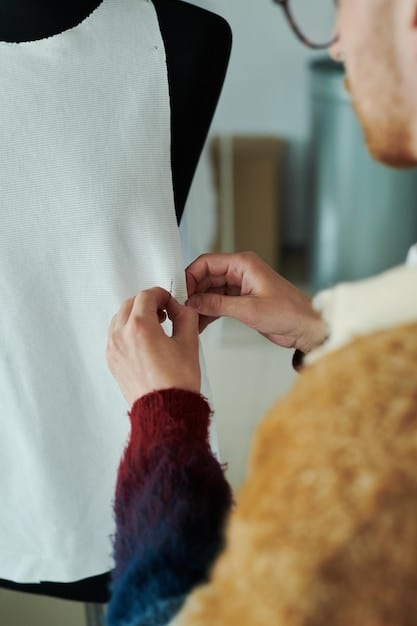 A close-up shot of a designer making adjustments to a garment backstage during a fashion show at New York Fashion Week. Focus is on the intricate details of the design and the designer's hands.
