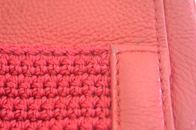 A close-up shot of a faux leather handbag, showcasing the texture and stitching detail. The bag is a neutral color, highlighting its versatility.