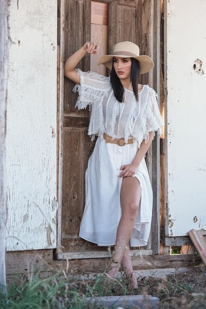 Shot of boho-chic outfit: white tee, maxi skirt, sandals, wide-brimmed hat.
