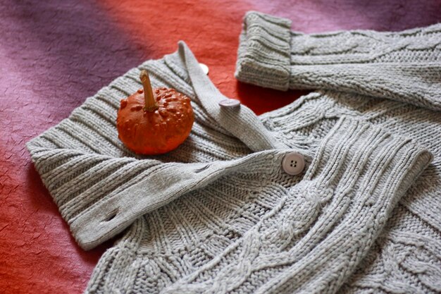 A close-up shot of essential layering pieces laid out on a bed in a US home. Items include a white turtleneck, a gray cardigan, a blue denim jacket, a black leather jacket, and a beige trench coat.