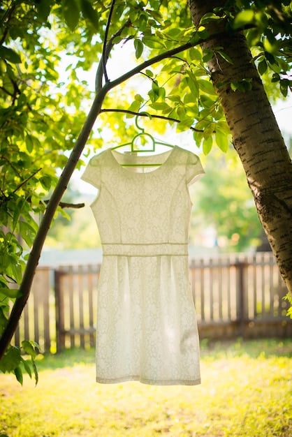 A clothesline strung between two trees in a sunny backyard. Various garments are hanging on the line, gently swaying in the breeze. The scene evokes a sense of natural, gentle drying that is kind to clothes and environmentally friendly.