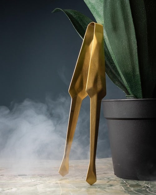 A close-up shot of sculptural high heels, showcasing intricate geometric designs and metallic finishes in gold and silver, set against a minimalist white background.