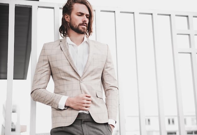 A stylish man wearing a modern grey suit with a crisp white dress shirt, no tie, and polished leather loafers, standing confidently in front of a blurred urban background. The suit has a slim fit and the overall look is effortlessly chic and professional.
